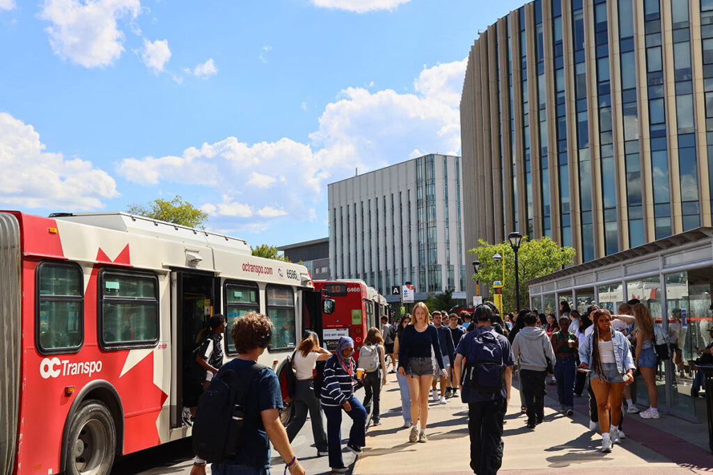 Students getting on and off a public bus with large buildings visible in the background.