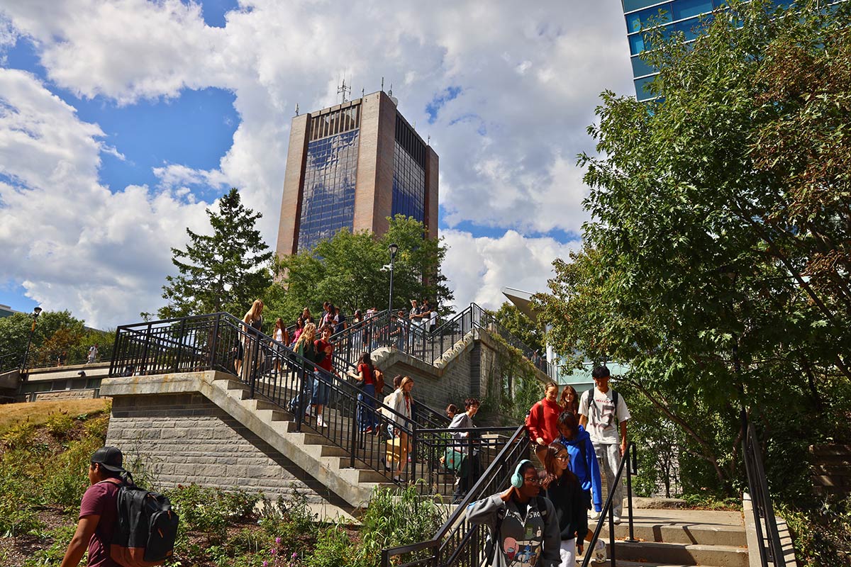 A large group of people ascending and descending outdoor staircase, with a large office building visible in the background.