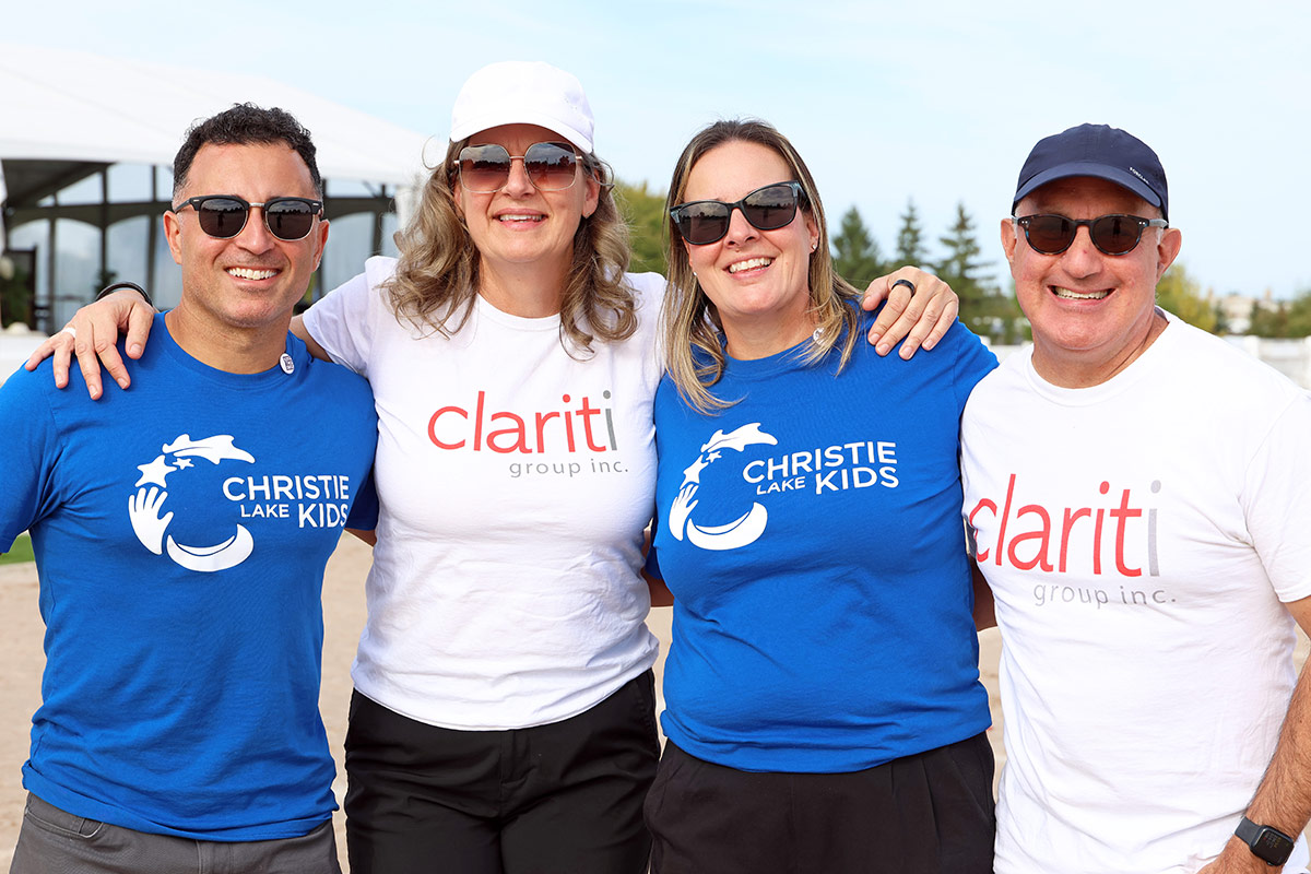 Reza Mashkoori poses outdoors with Christie Lake Kids and Clariti Group team members at a charity sports event.