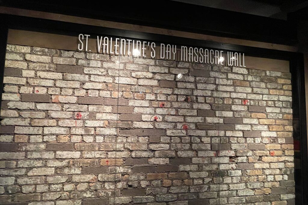 A brick wall with a sign that says St. Valentine's Day Massacre Wall, part of a dark tourism tour.