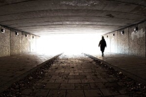 A silhouette of a person walking though a dark tunnel on a ghost walk, symbolizing dark tourism.