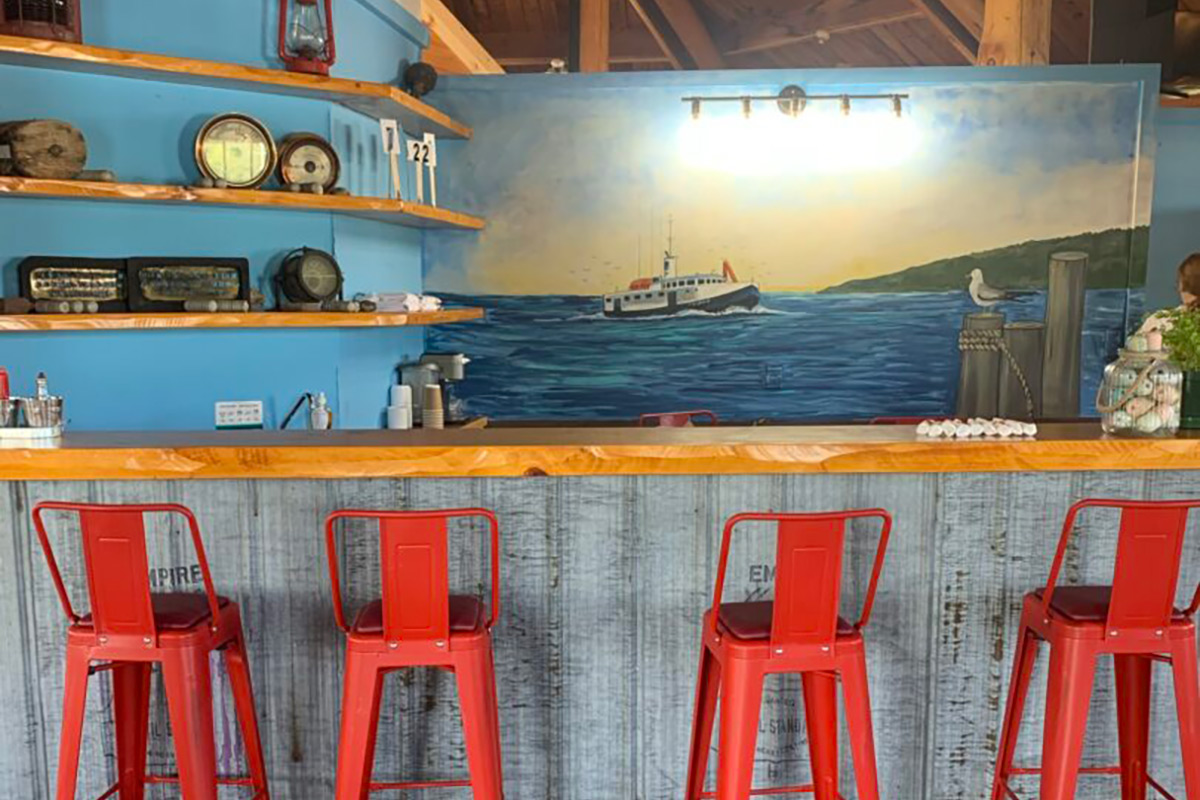 Four red bar stools sitting in front of a bar.