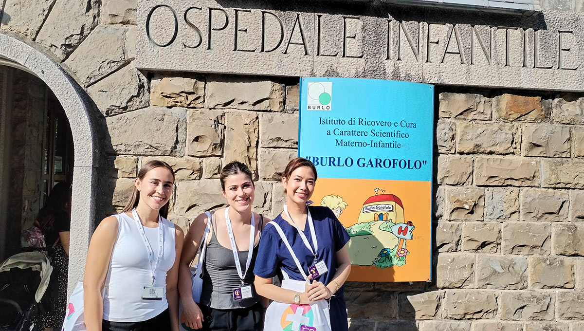 Three health sciences students posing for a group photo outside of an old stone building.