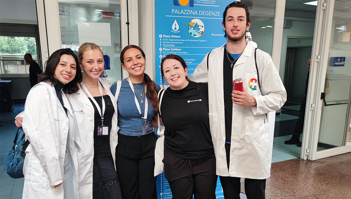 Several members of the medical community posing for a group photo in front of a hospital.
