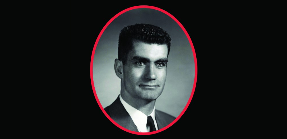 A black and white professional headshot of a man wearing a suit.