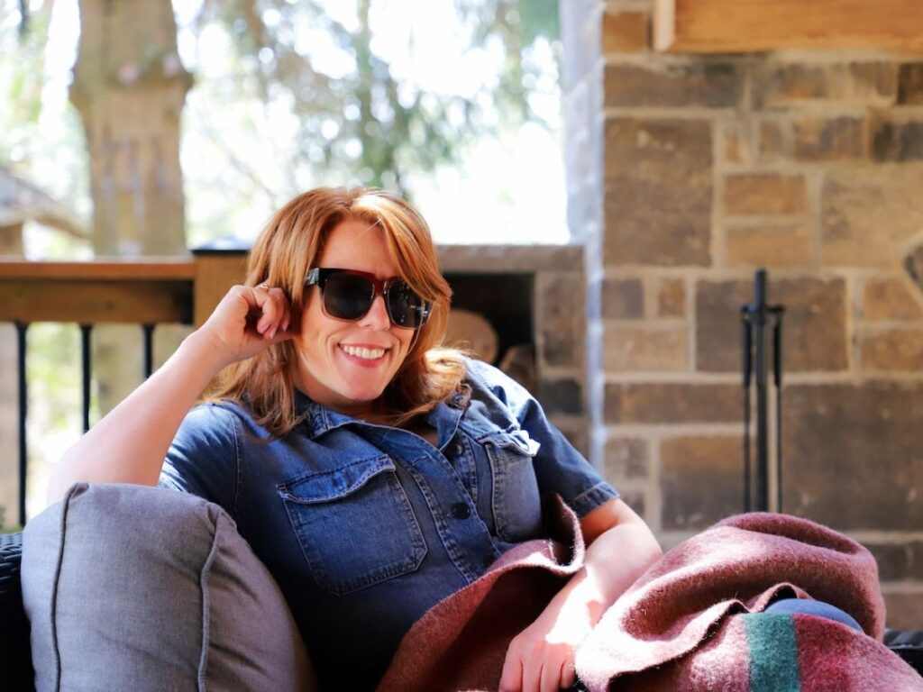 Public relations professional Mandy Sinclair reclines on a chair on an enclosed patio outside.