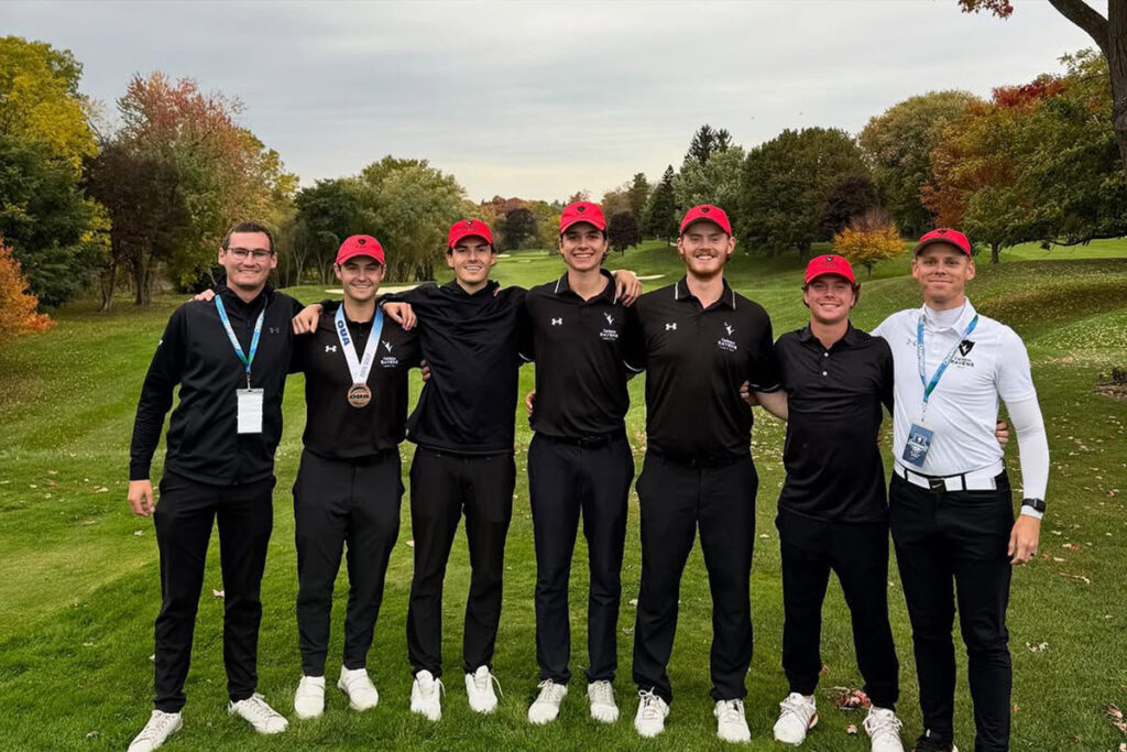Six members of a golf team pose for a group photo on a golf course.