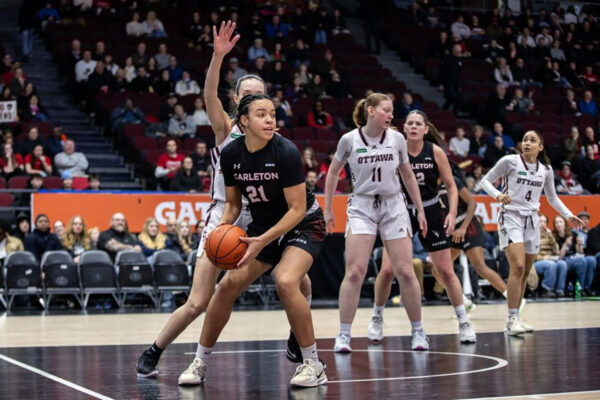 A basketball player gets ready to drive towards the net as a defender attempts to block her.