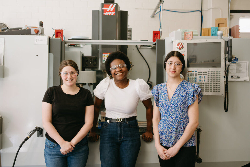 Three women pose in a laboratory