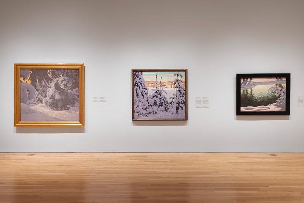 Three paintings on a wall inside an art gallery.