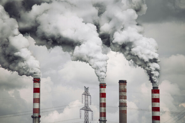Industrial smokestacks releasing CO2 emissions highlighting need for carbon capture storage and net zero solutions.