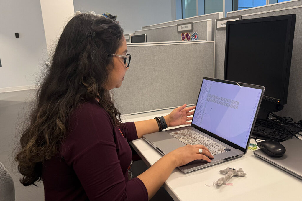 A woman with glasses working on a laptop.