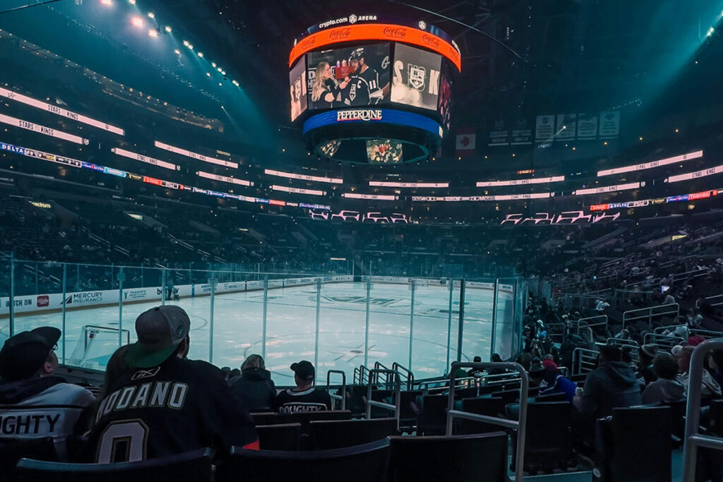Fans in the stands watch an interview being conducted at ice level with an NHL hockey player.
