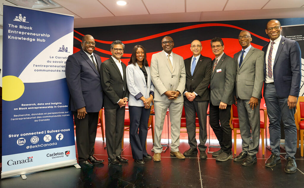 Eight people wearing suits pose for a group photo.