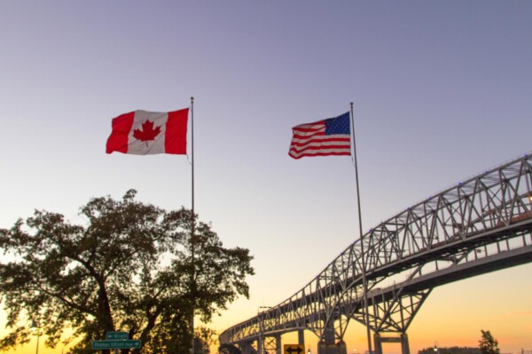 Flags of Canada and the USA, with the Blue Water Bridges international in the background.