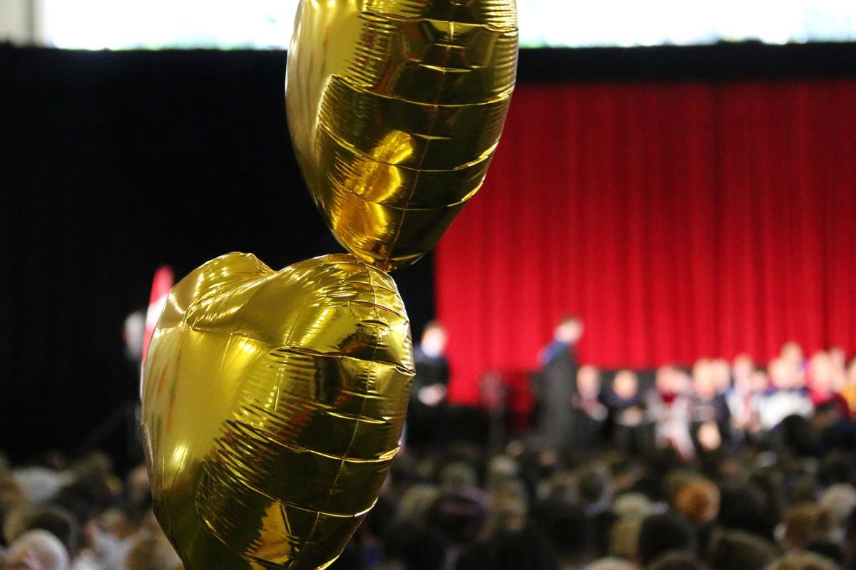 Gold balloons floating over a crowd.