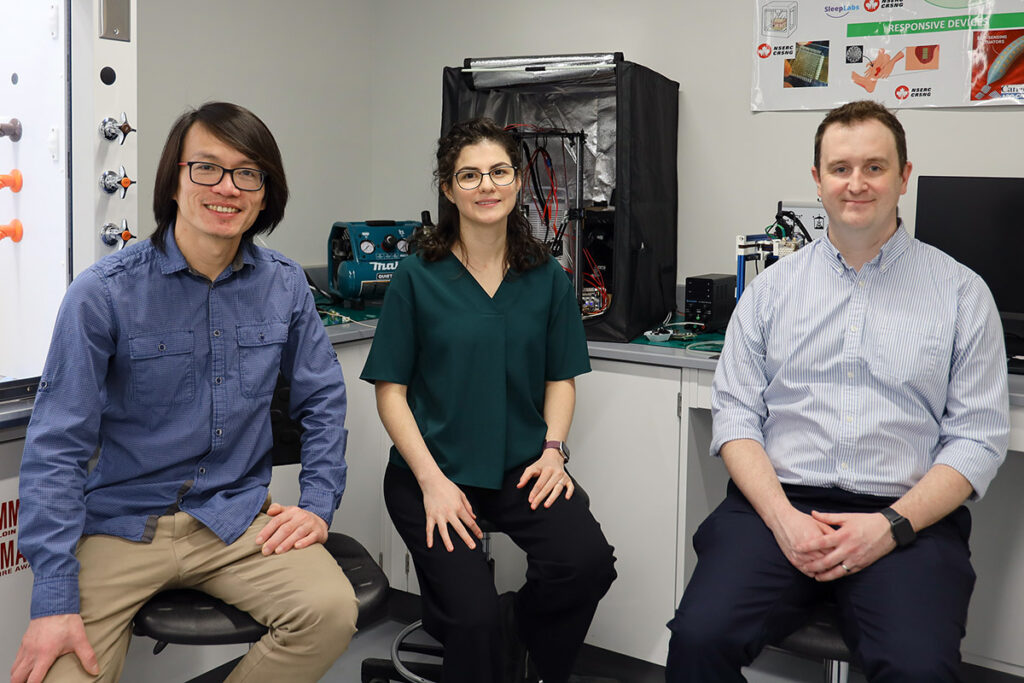 Three people posing for a photo while seated in a lab.