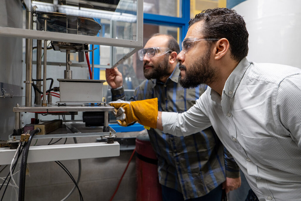 Two people leaning in close to look at a piece of lab equipment.