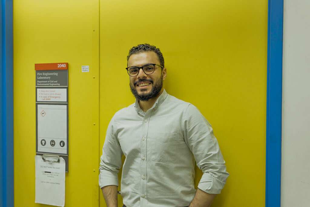 A man wearing glasses smiles for the camera while posing for the camera.