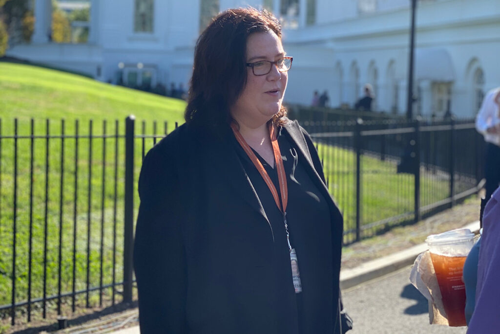 A woman engages in conversation while standing outside of The White House.