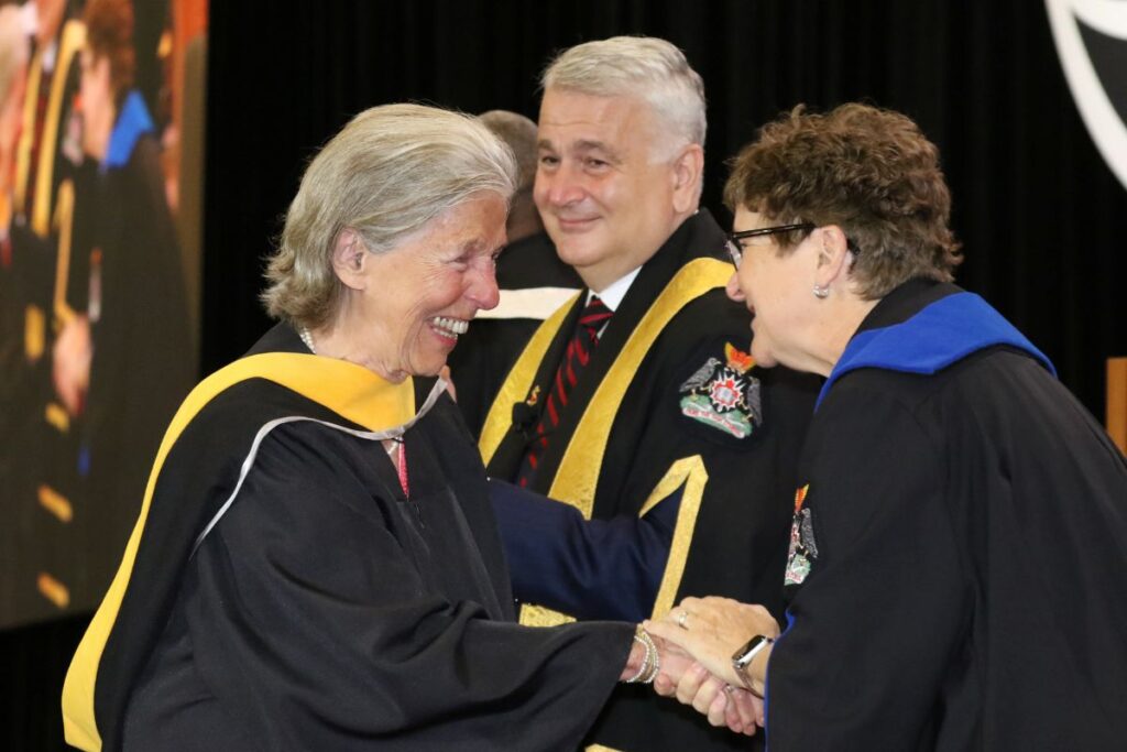 Ann Laubstein shakes Board Chair Beth Creary's hand as she receives her degree.