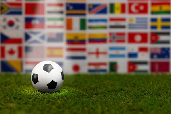 Global soccer concept with international flags circle and ball on grass.