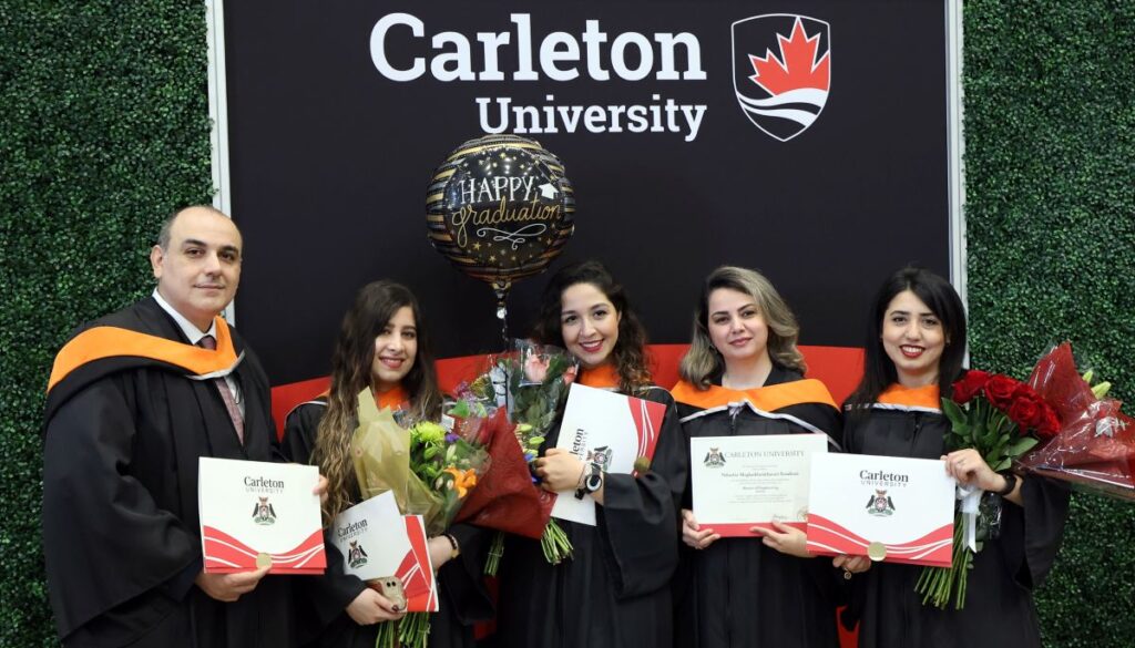 A crowd of five students pose after receiving their degrees