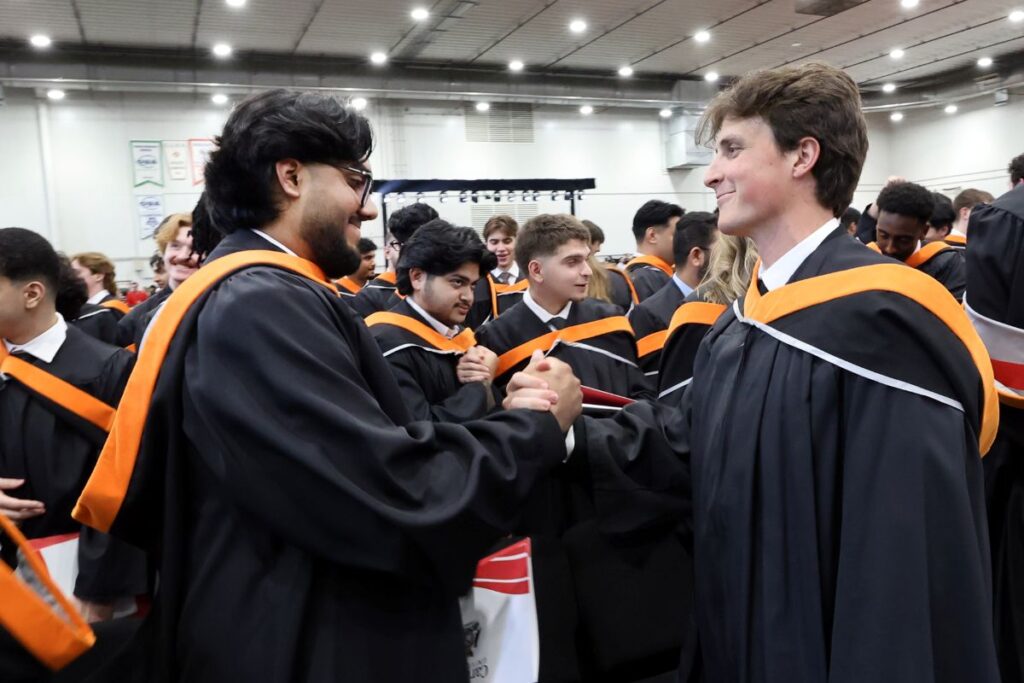 Graduating students clasp hands in celebration at convocation.