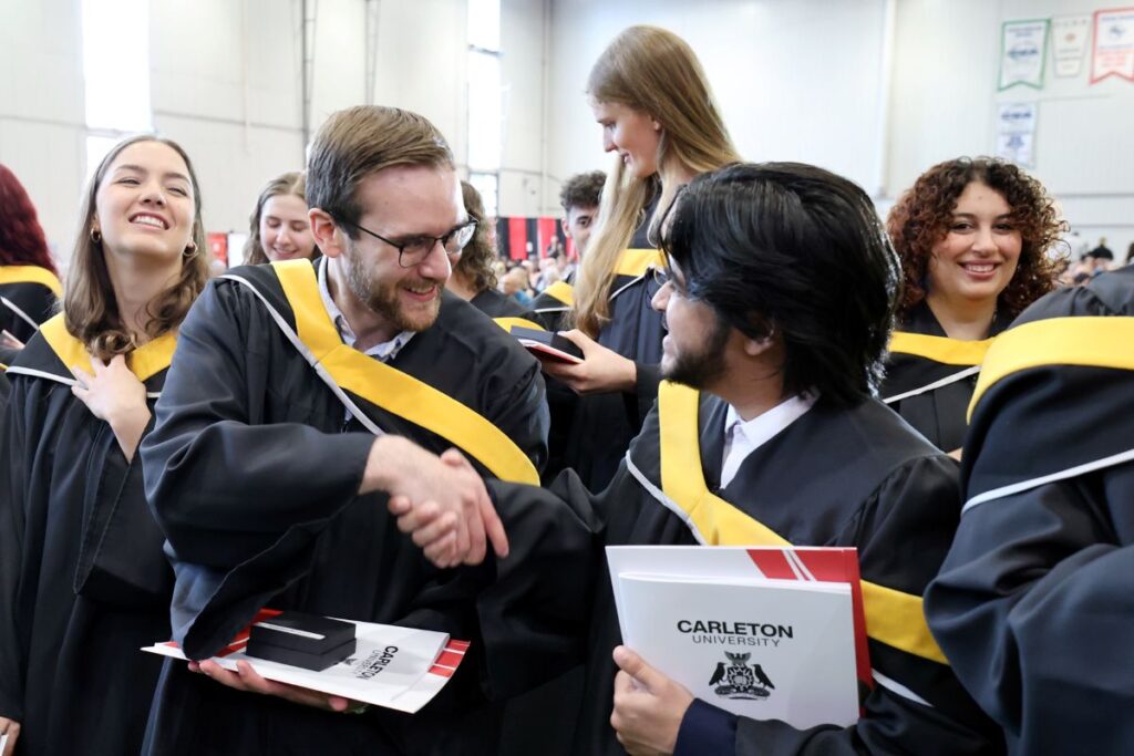 Graduating students shake hands in congratulations at Spring Convocation 