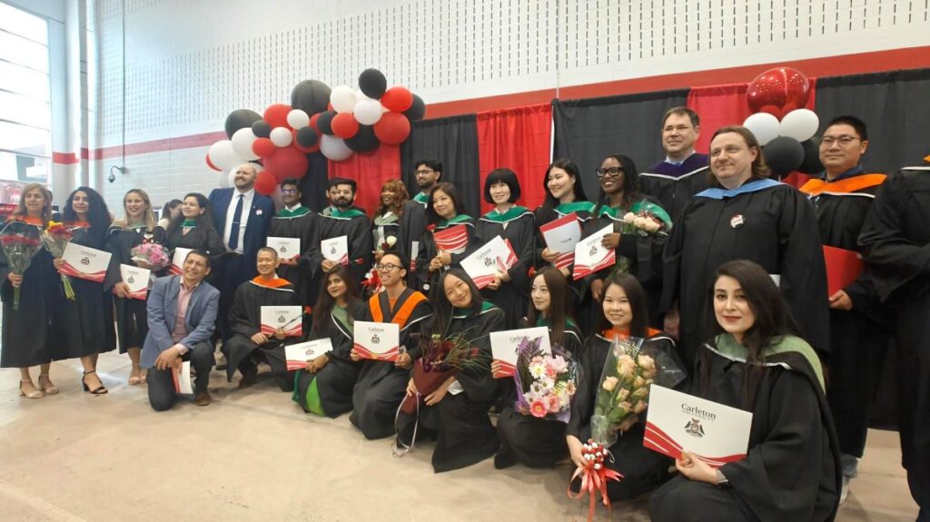 A crowd of graduating students from the Sprott School of Business's TIM Program pose in the Ravens Nest