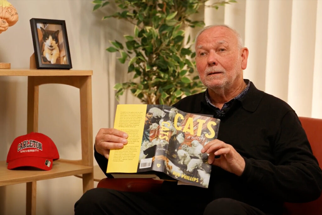 Rod Phillips holds up his book Cat: A History.