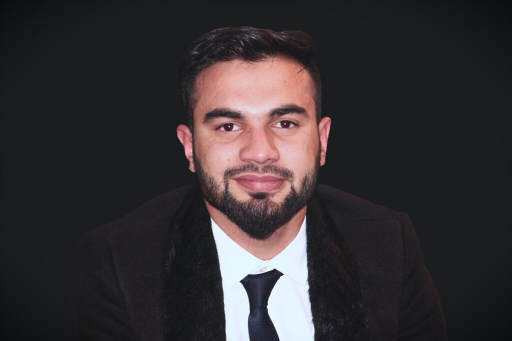 A man in a suit smiles for the camera.