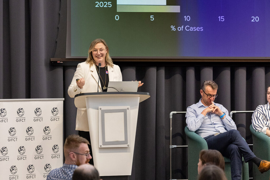 A woman speaks from a podium during a conference.