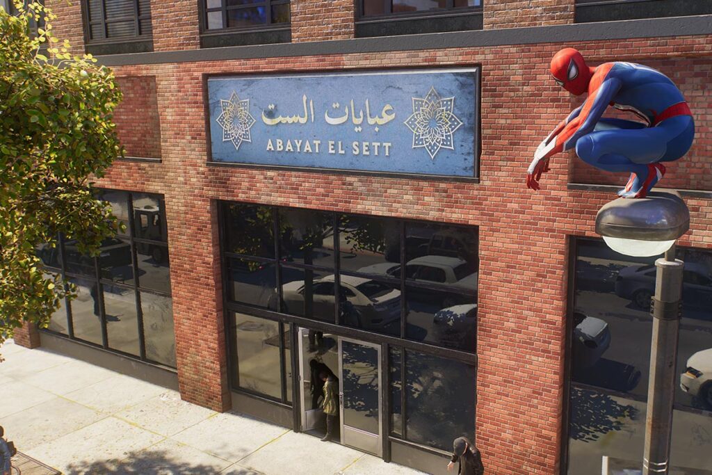 A still from Marvel's Spider-Man 2 showing Spider-Man perched on a streetlight outside Abayat El Sett in New York City.