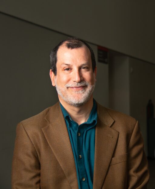 A man in a brown jacket poses for a photo. 