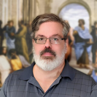 A headshot of a man with glasses wearing a dress shirt.
