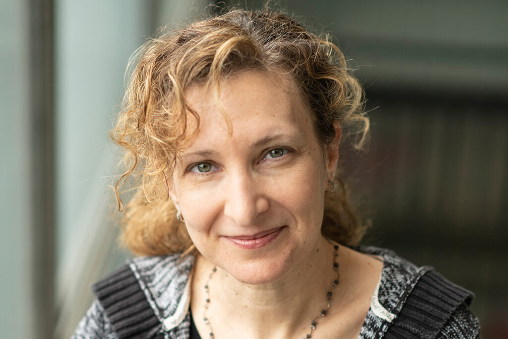 A headshot of a woman wearing a grey wool sweater.