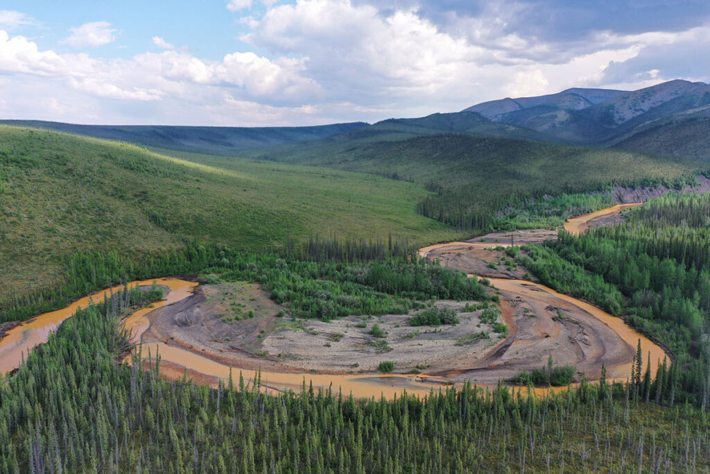 Aerial view of stream flowing through Arctic permafrost landscape.