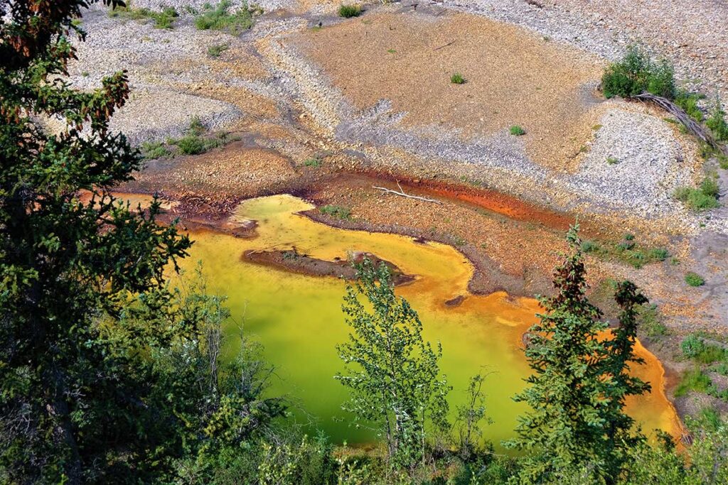 Acid mine drainage polluting stream with orange and green water.