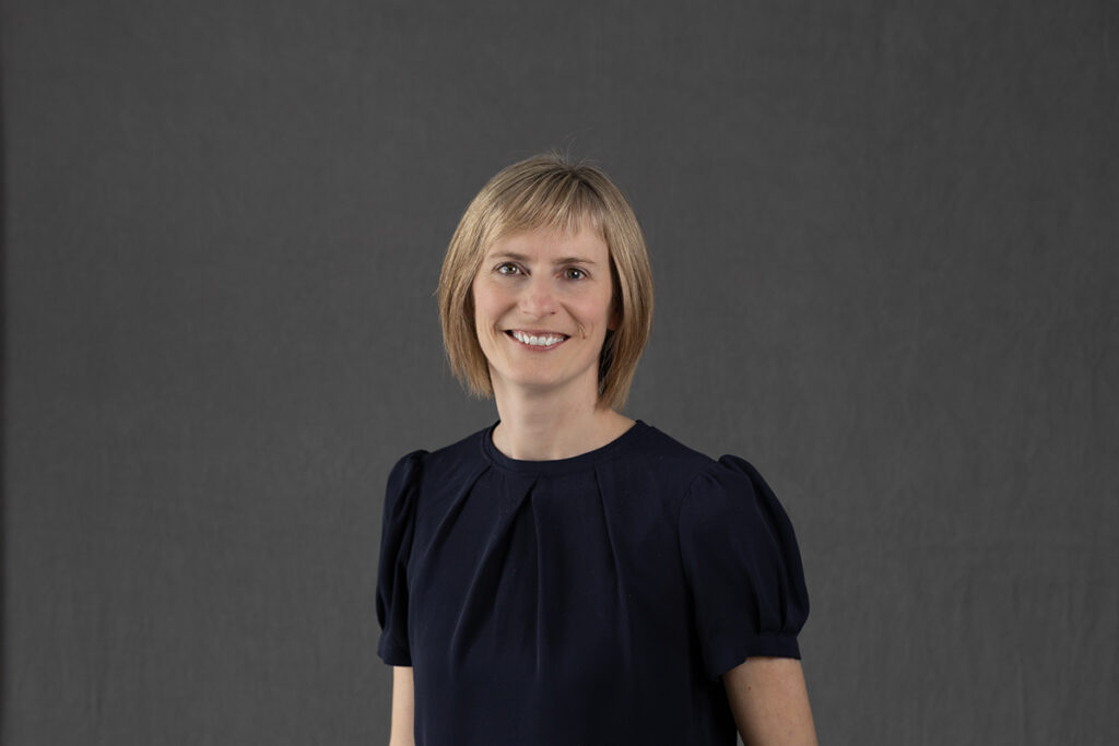 Jenny Bruin smiling against a grey background.