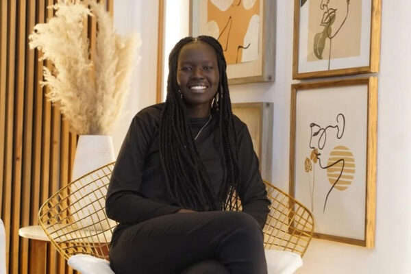 Nyabuol Biel Gang smiles while seated in a chair.