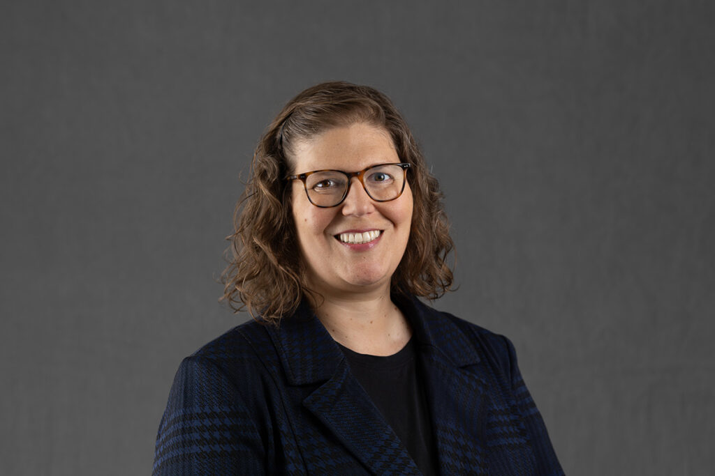 Laura Horak smiling against a grey background.