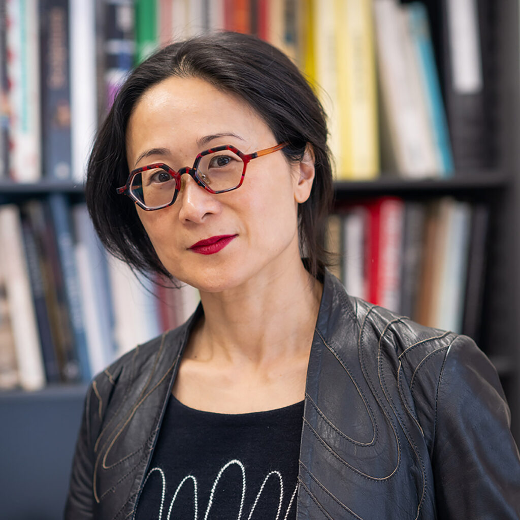 Ming Tiampo poses for a photo in front of a bookshelf.