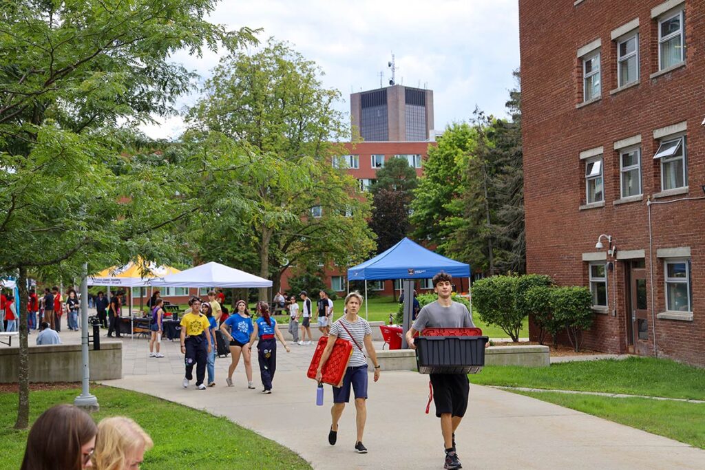 Several people walking down a path surrounded by brick buildings.