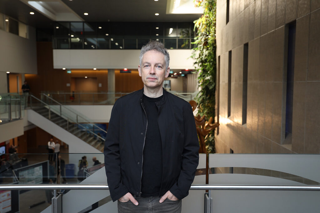 A man poses for a photo with his hands in his pockets.