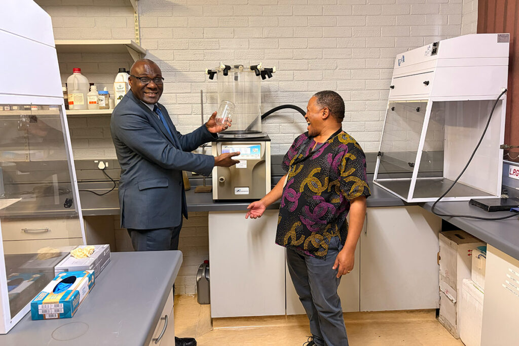 Wisdom Tettey speaks with a researcher during a laboratory tour.