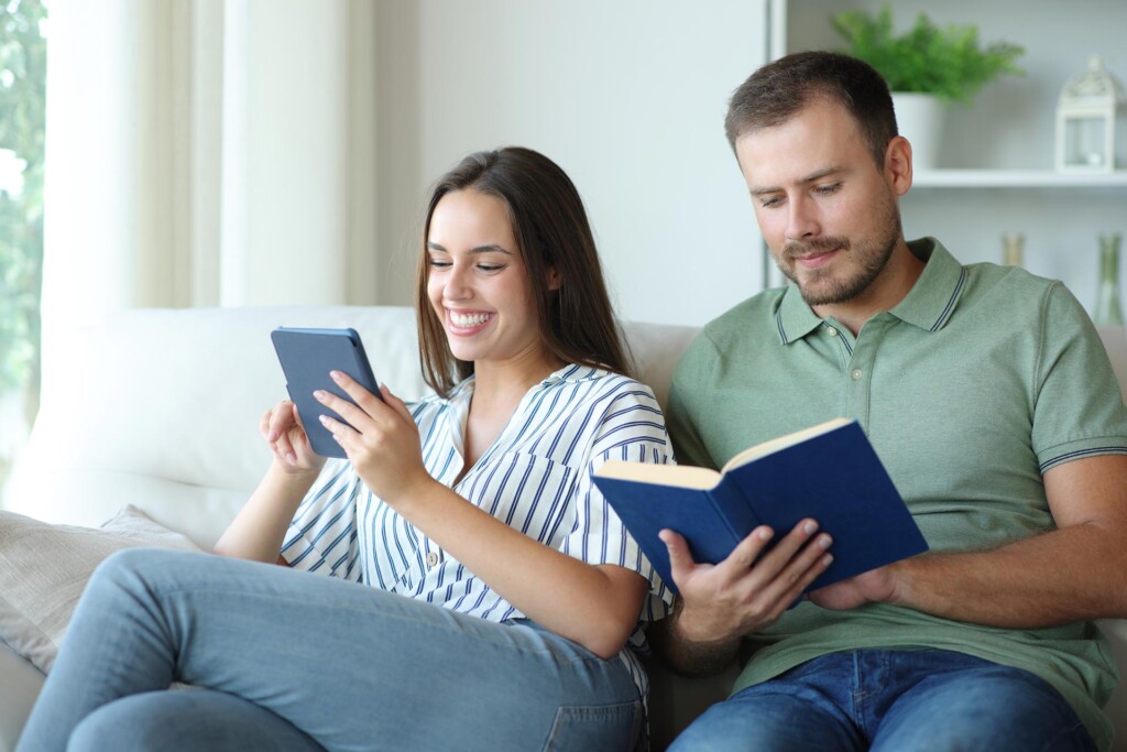 Couple reading paper book and ebook at home.