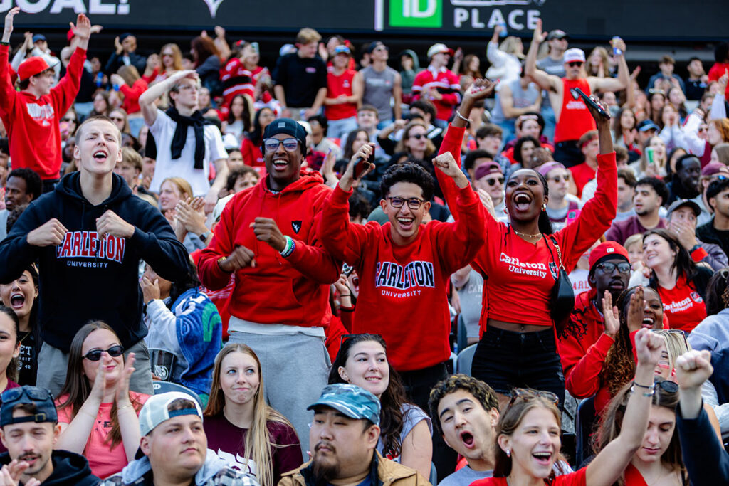 Carleton fans in red and black cheer in the stands at TD Place.