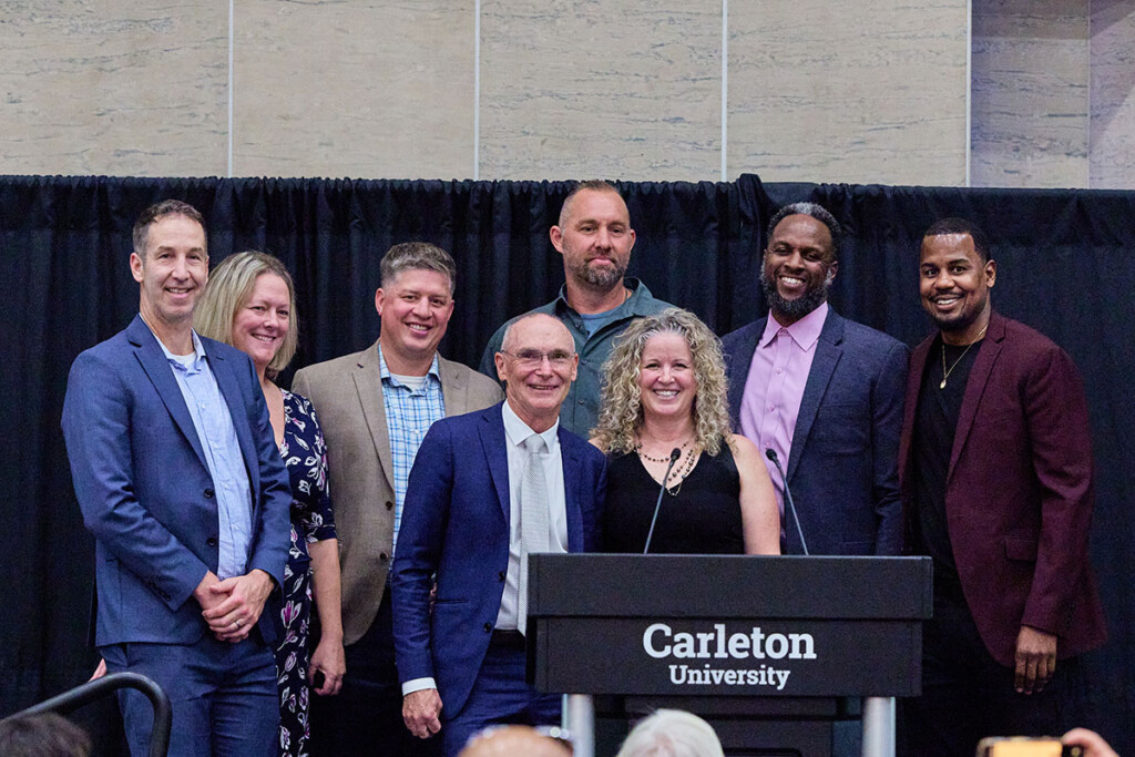 Inductees of the Ravens Hall of Fame and event organizers pose for a podium stage photo.