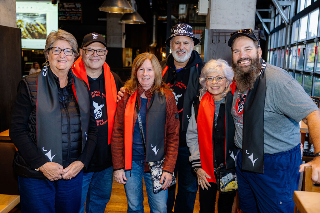 Attendees of the Pancaker alumni event dressed in Carleton gear pose for a photo.